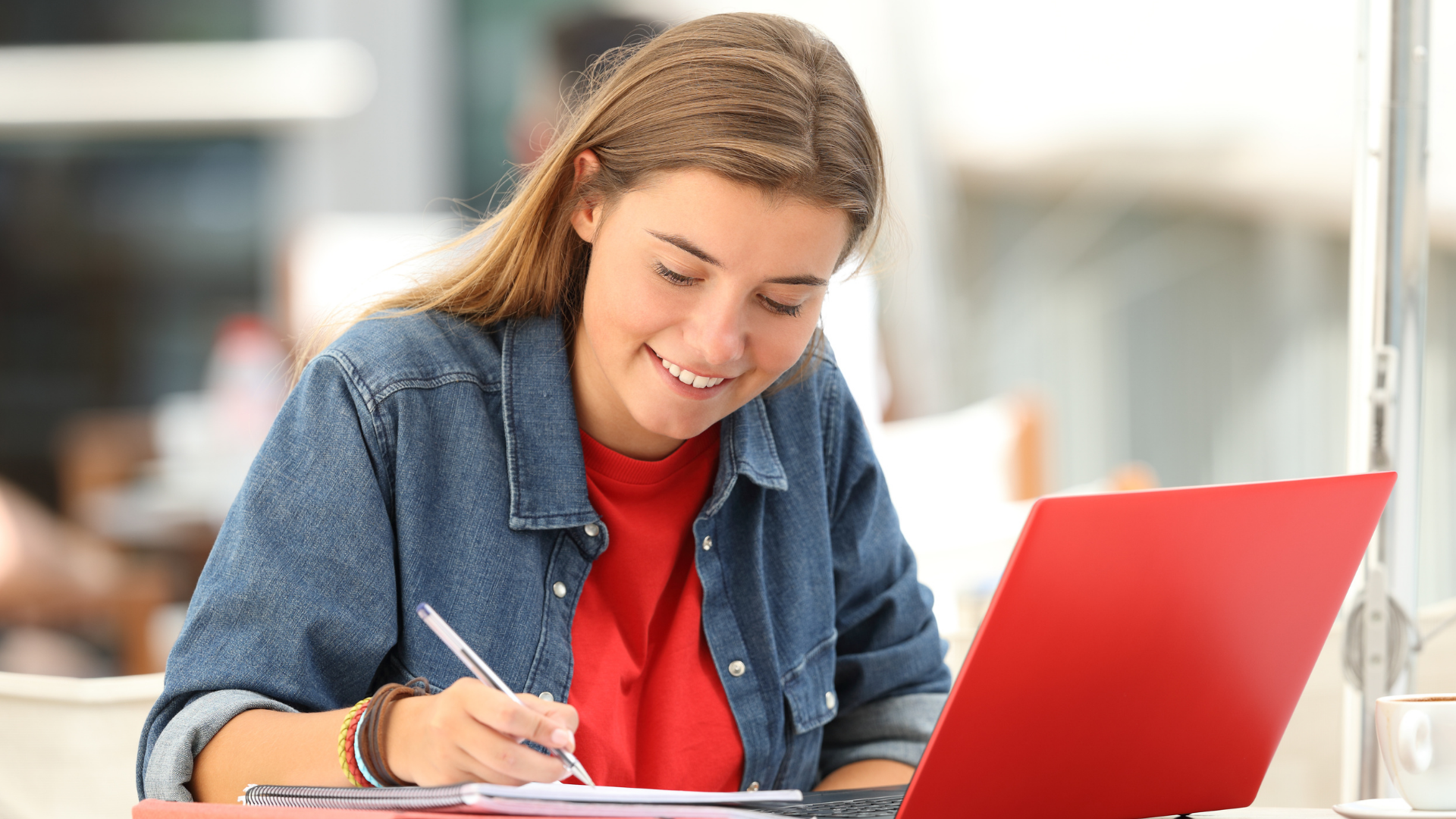 A young girl smiles as she looks at her computer and completes her college application